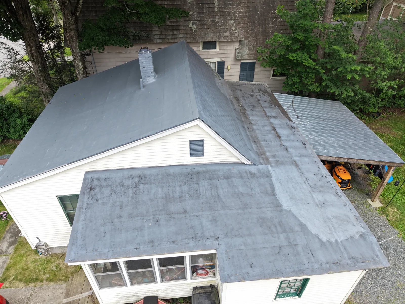Aerial overhead view of a residential roof showing multiple roof planes, a flat section, and a metal carport — Brattleboro, VT