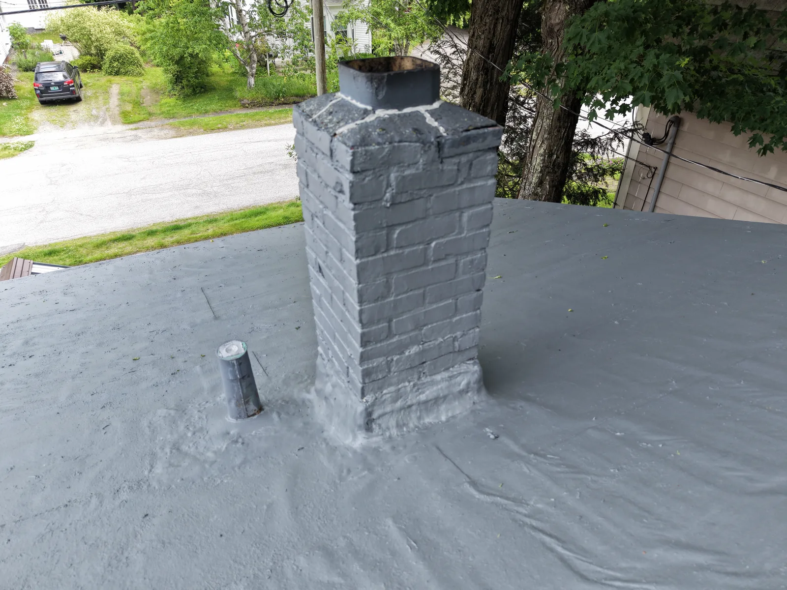 Close-up drone photo of a brick chimney on a flat roof showing mortar cracks and surface wear — Brattleboro, VT