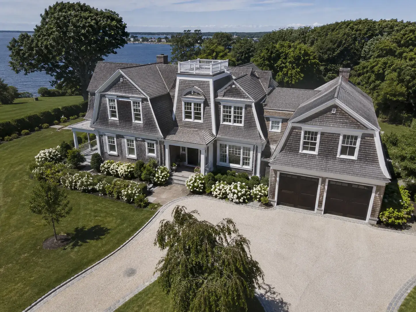 Aerial drone view of a premium New England shingle-style home near water