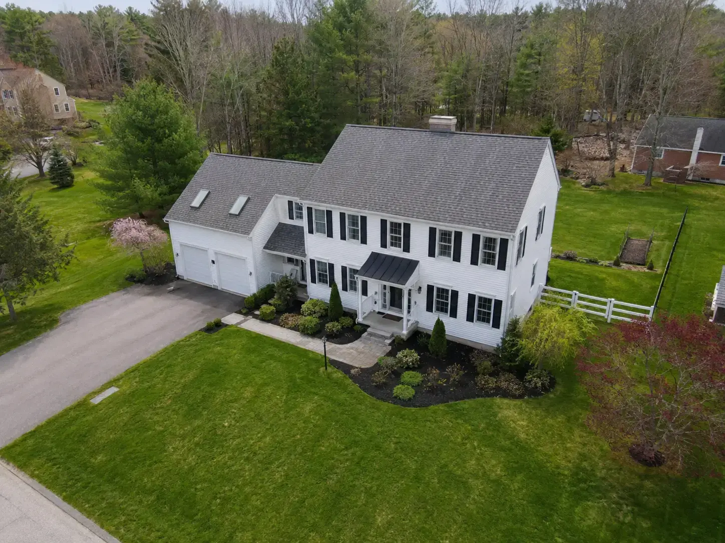 Aerial drone view of a suburban New England colonial property in spring